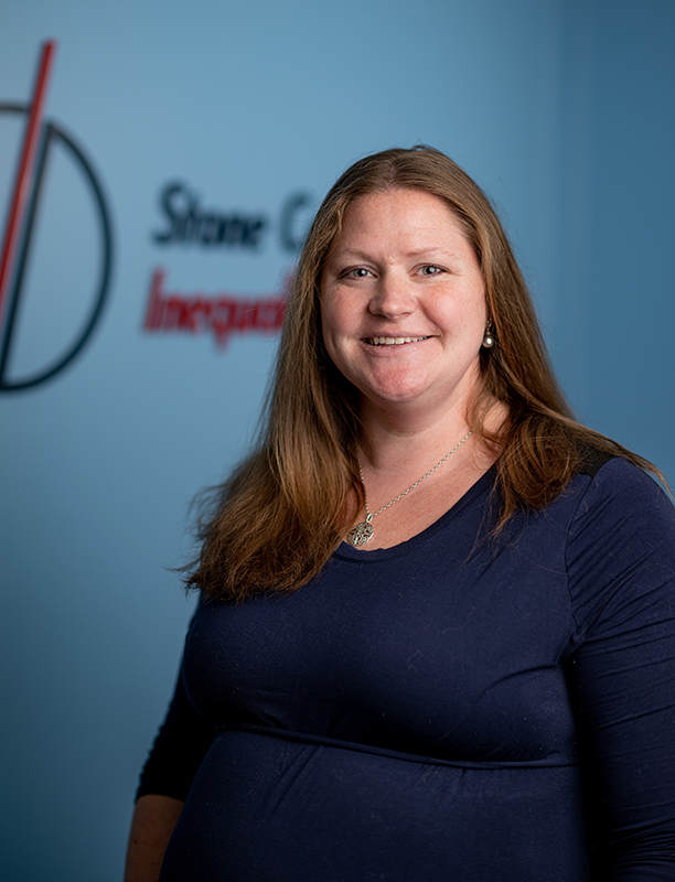 Melissa Bora, Stone Center Program Manager, stands in the space in front of the logo in a head shot.