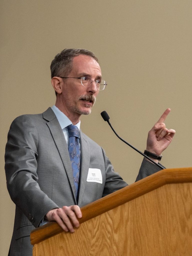 Isaac Martin stands presenting at a podium.